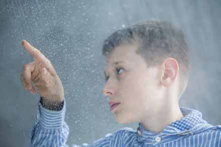Autistischer Junge zählt Regentropfen an einer Scheibe