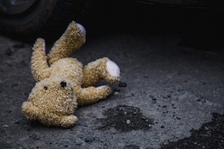 Verlorener Teddybär liegt auf nassem Asphalt